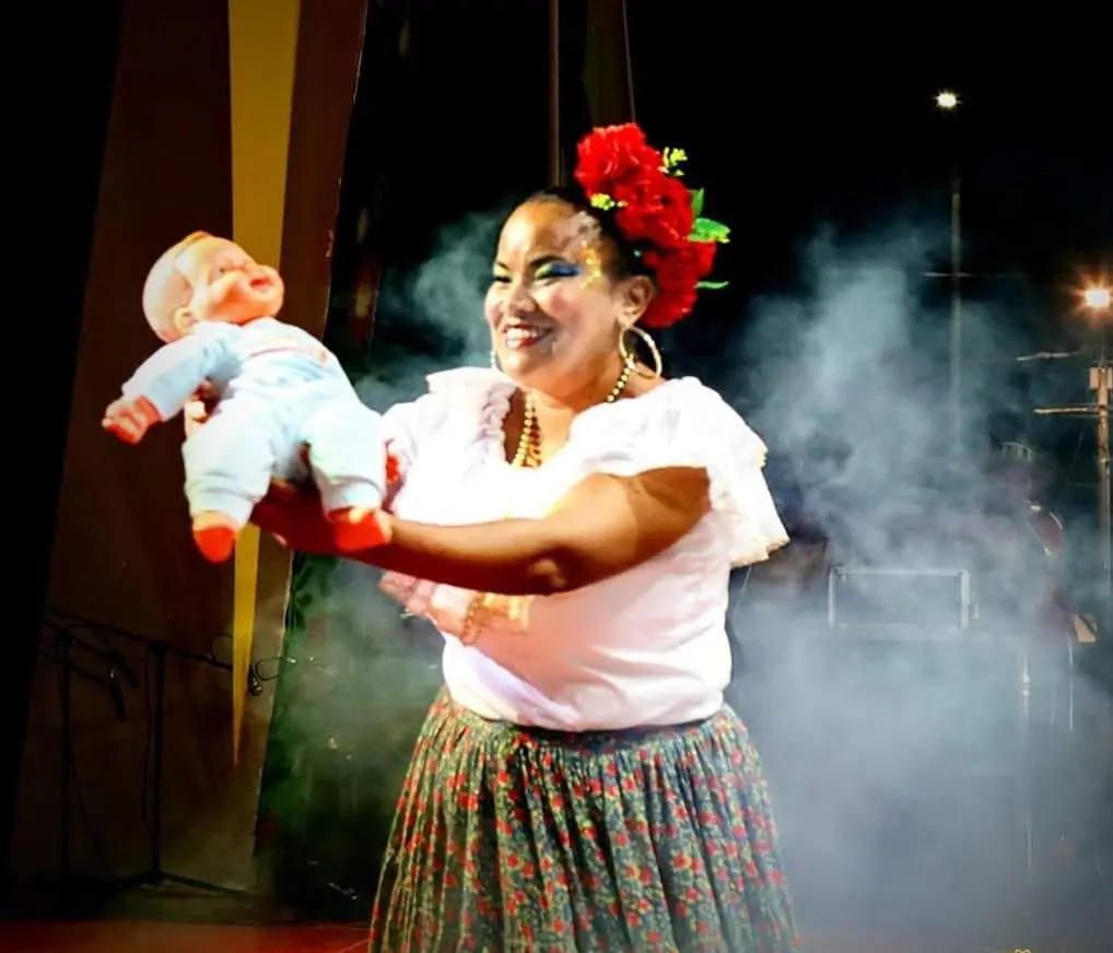 Cantadora adulta con pañoleta cantando frente al público.
