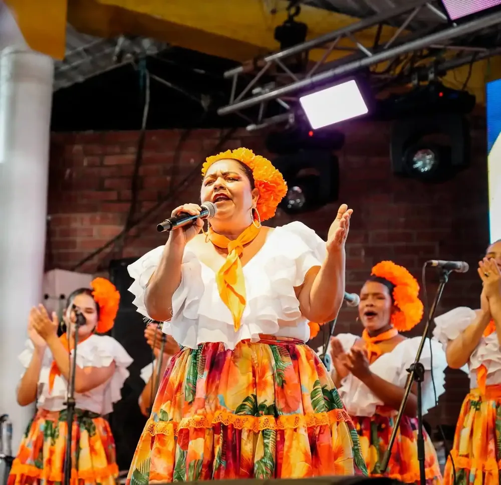 Cantadora con vestuario típico cantando con los ojos cerrados.