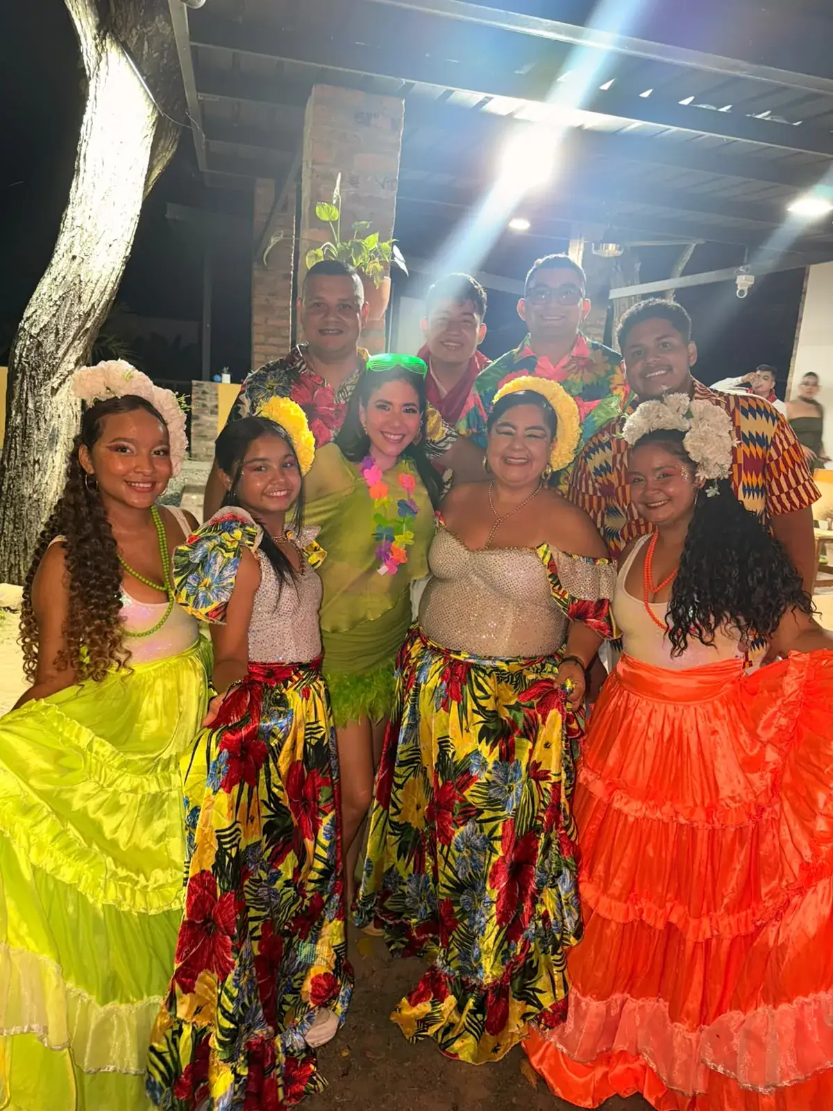 Bailadores con faldas de colores posan junto a los invitados durante la animación de un evento nocturno.